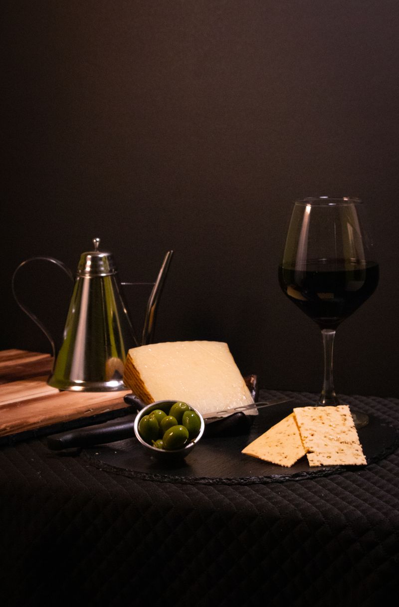 A sophisticated setup of red wine, cheese, olives, and crackers for an elegant indoor gathering.